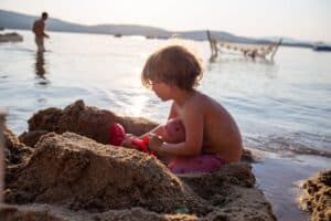 A boy enjoying sensory play with sand at the beach