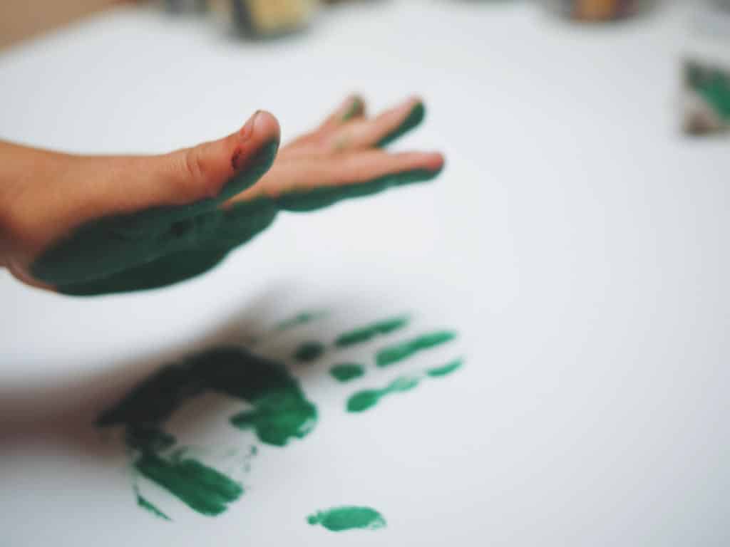 A child making a hand print with finger painting