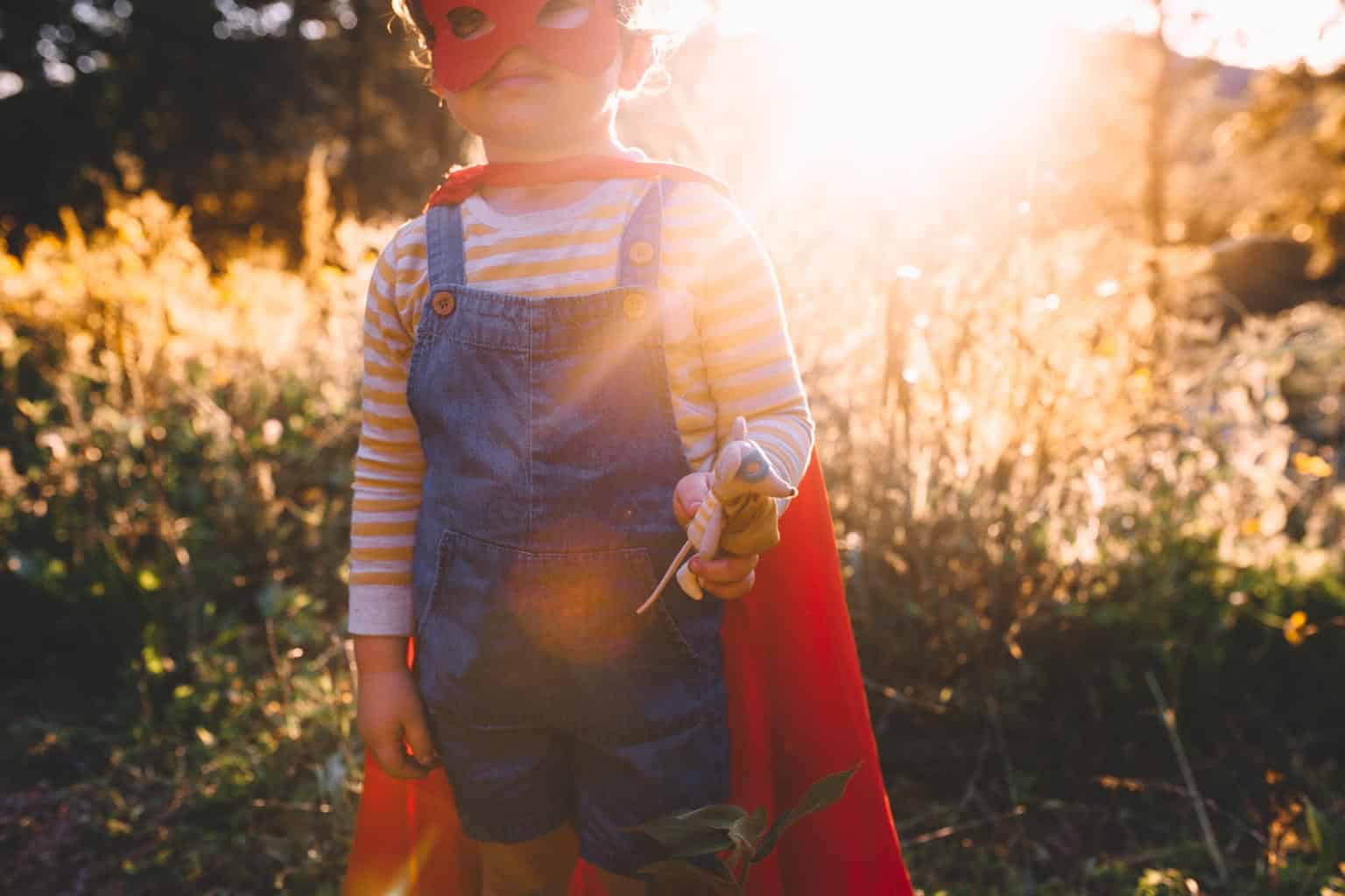 Boy in superhero costume holding a toy